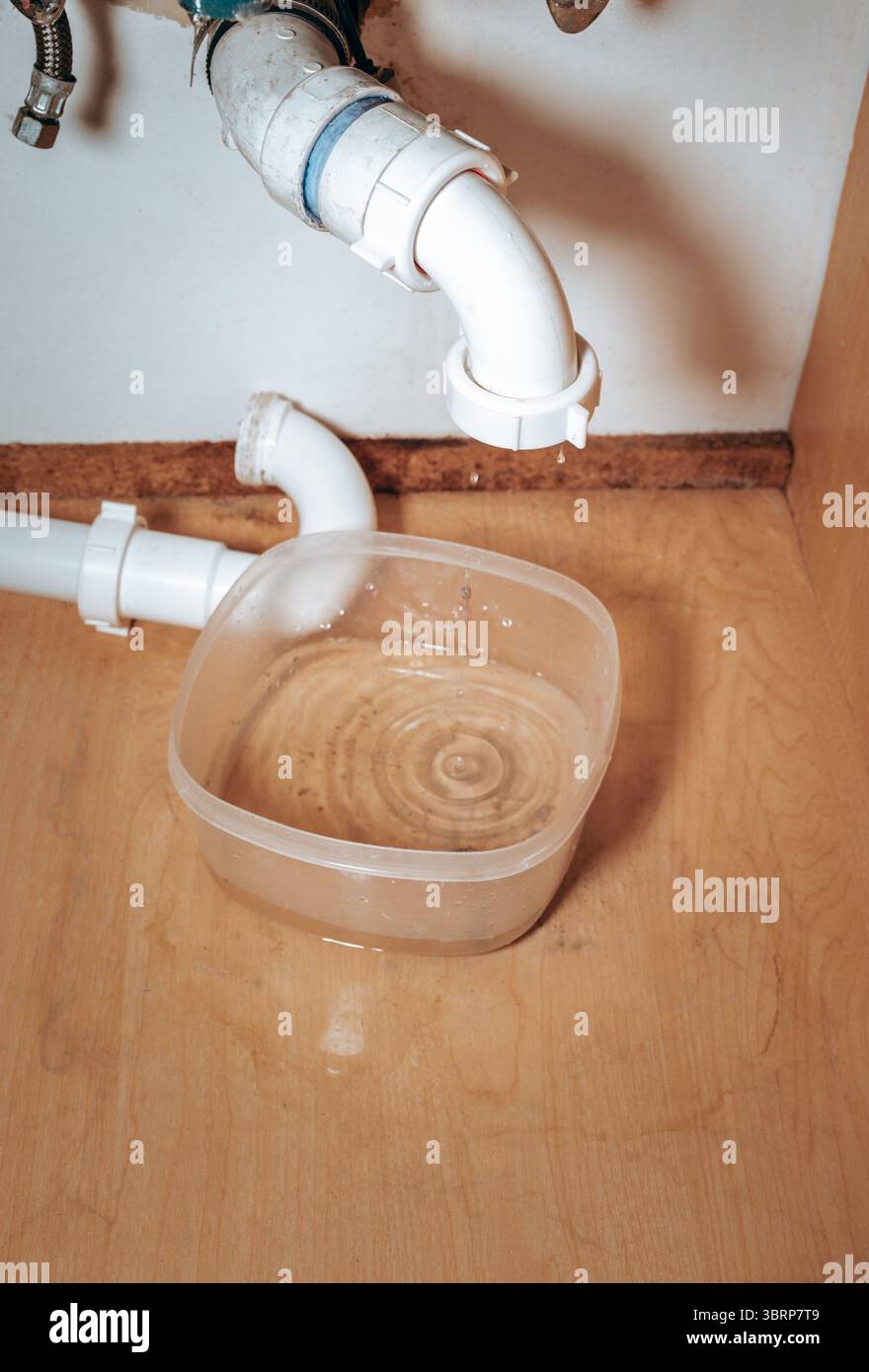 Immagine ravvicinata che mostra un tubo a trappola P scollegato e che perde sotto il lavandino del bagno. Riparazioni domestiche, problemi idraulici Foto Stock