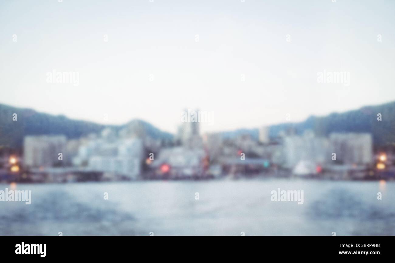 Lo skyline costiero della città si presenta in un design piatto sull'acqua calma, con edifici e colline costiere Foto Stock