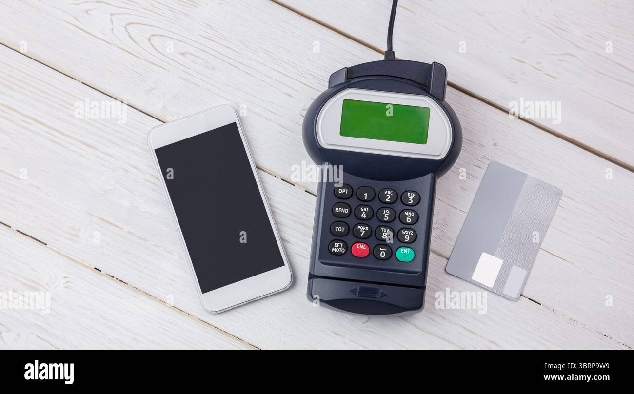 I dispositivi di pagamento vengono visualizzati su un tavolo bianco, con design piatto e smartphone, lettore e carta di credito Foto Stock