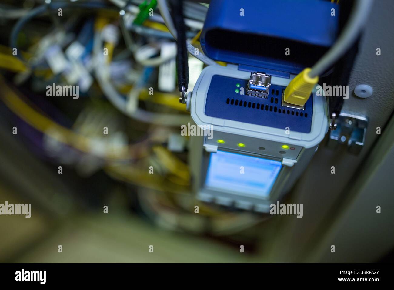Tester portatile che visualizza la diagnostica con LED verdi, cavo giallo, cavi patch all'interno del rack Foto Stock