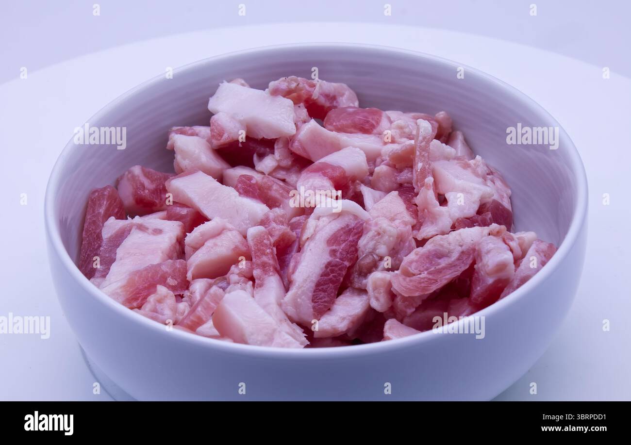 Guanciale stagionato, guancia di maiale stagionata, tagliata in un recipiente bianco. Foto Stock