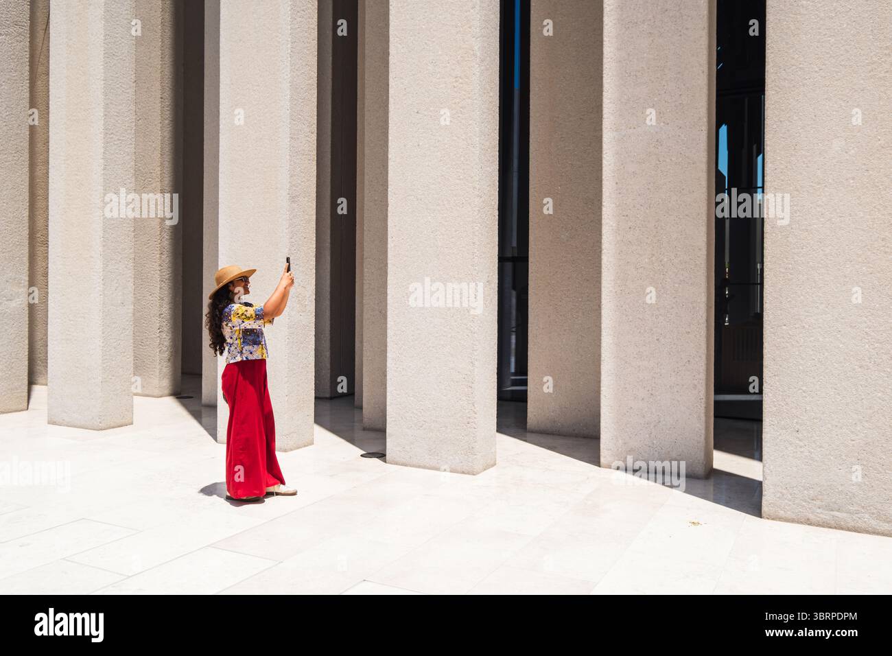 Moderna struttura in cemento contemporanea con il turista femminile, fotografando colonne architettoniche, gioco di luci e ombre Foto Stock