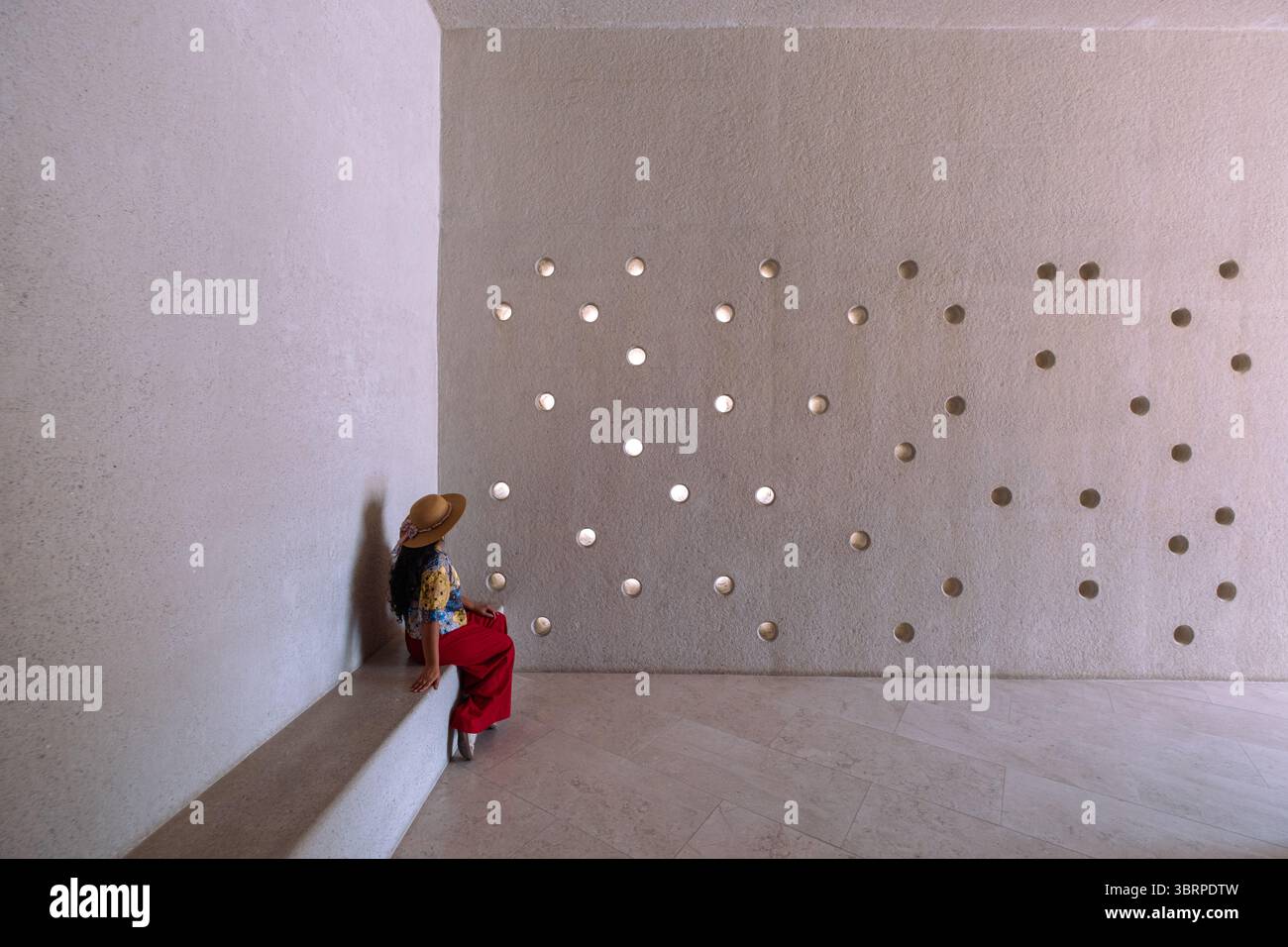 giovane donna turistica seduta all'interno di un museo moderno contemporaneo con pareti in cemento perforato Foto Stock