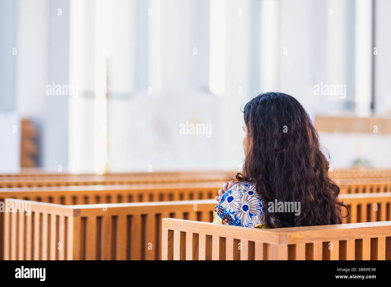 Tranquillo interno bianco della Chiesa con donna in preghiera Foto Stock
