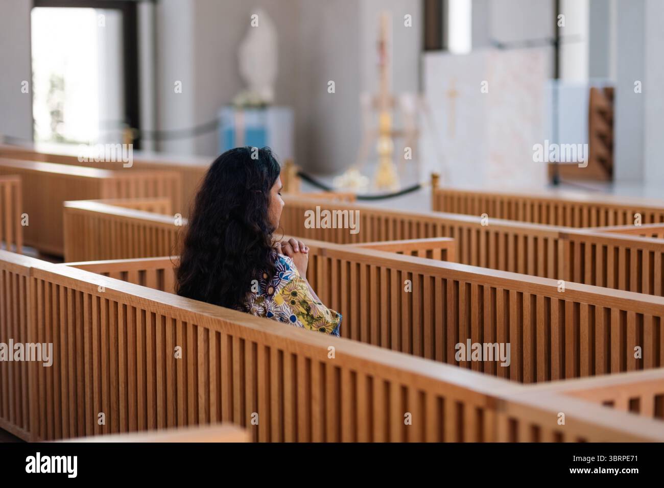 Moderno interno della chiesa cattolica con donna che prega, panchina in legno all'interno della chiesa Foto Stock Moderno interno della chiesa cattolica con donna che prega, panchina in legno all'interno della chiesa Foto Stock