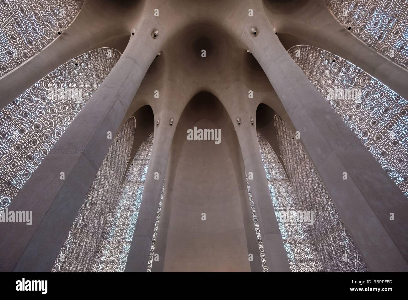 Architettura interna della moderna Moschea con alti archi e pareti a motivi geometrici, una miscela di elementi di design moderni e tradizionali. Nessuna persona visibile. Foto Stock