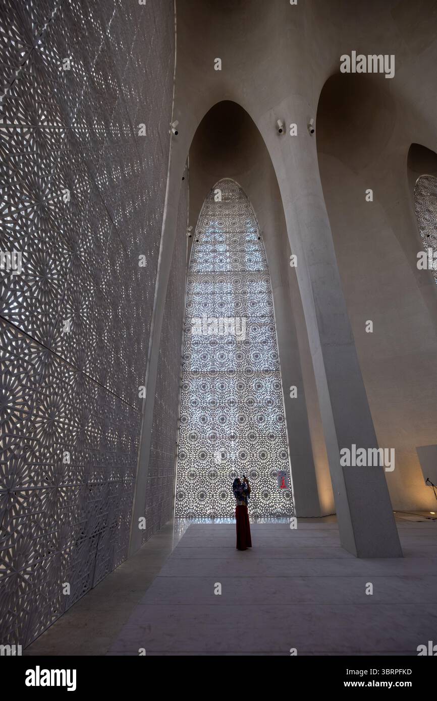 Interni moderni della moschea con una donna in tradizionale abito abaya, architettura in bianco e nero della moschea Foto Stock