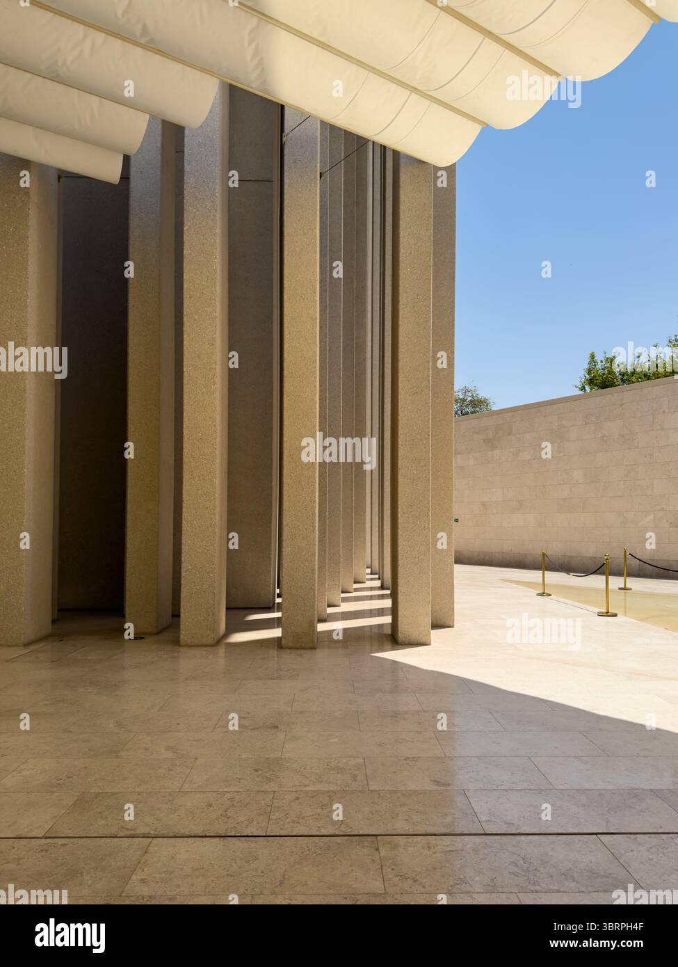 Edificio dall'architettura contemporanea con colonne, luci dinamiche e motivi d'ombra sul pavimento e sulle pareti Foto Stock