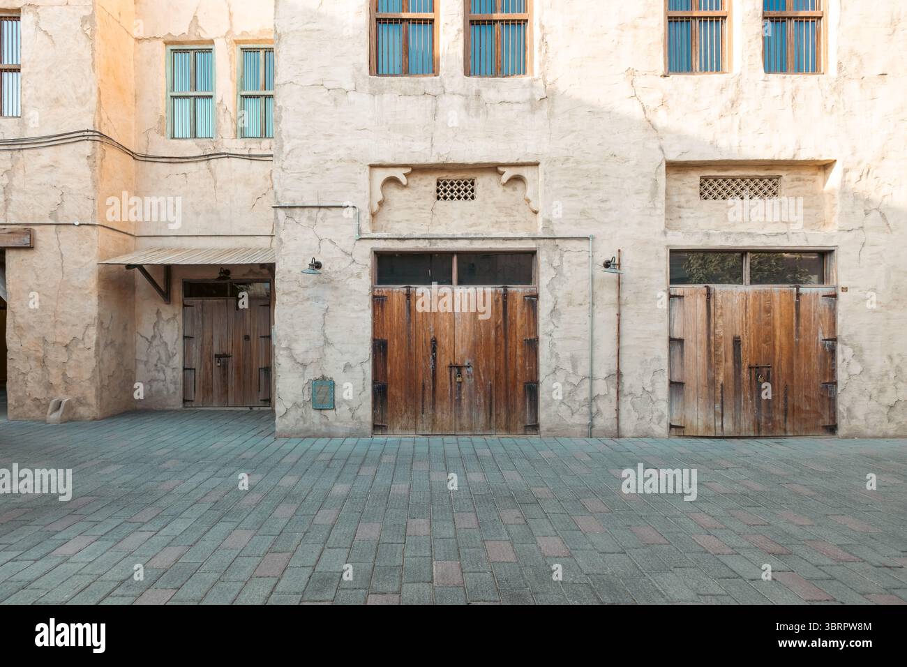 facciata di un vecchio edificio con pareti in pietra e porte e finestre in legno, strada della città vecchia con porte in legno e finestre color acqua Foto Stock