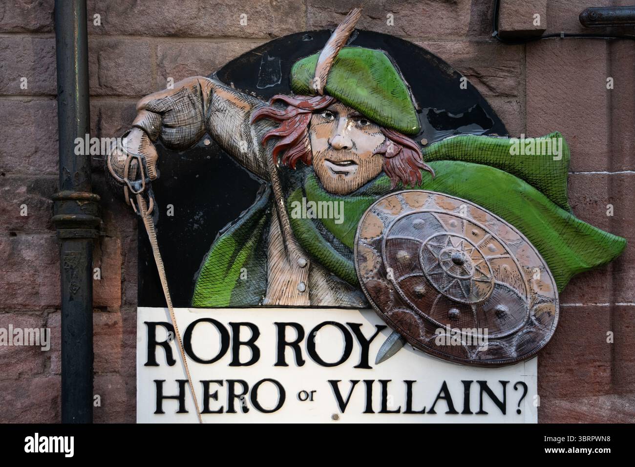 Sfrontato, controverso figura storica scozzese Rob Roy in berretto verde e mantello con spada e scudo. Foto Stock