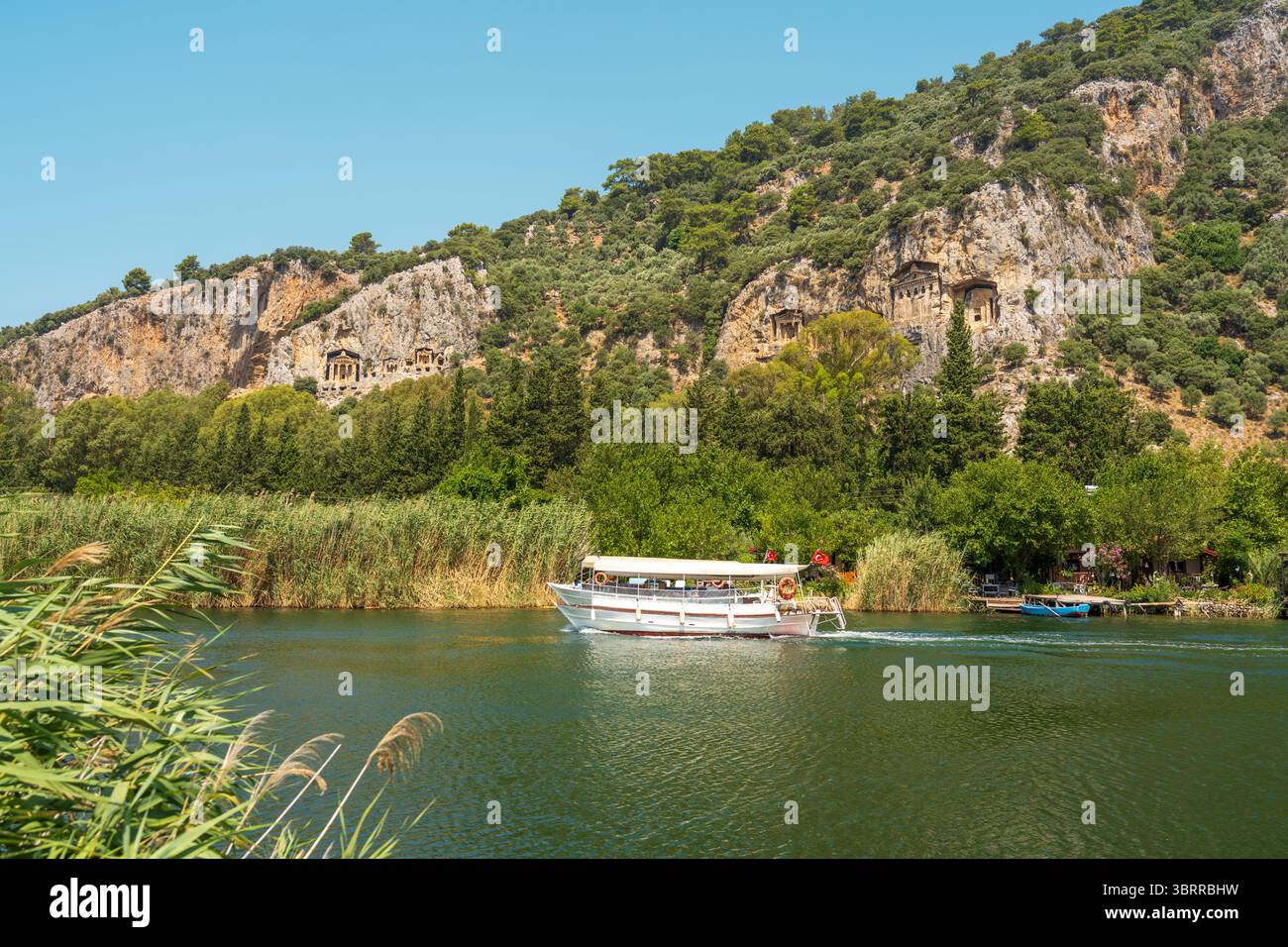 Tour in barca sul fiume Dalyan con vista delle tombe rocciose di Kaunos sulle scogliere Foto Stock