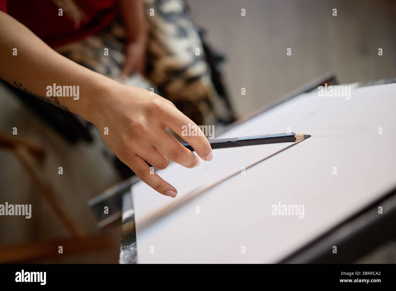 Donna che disegna schizzo su carta con matita in interni Foto Stock