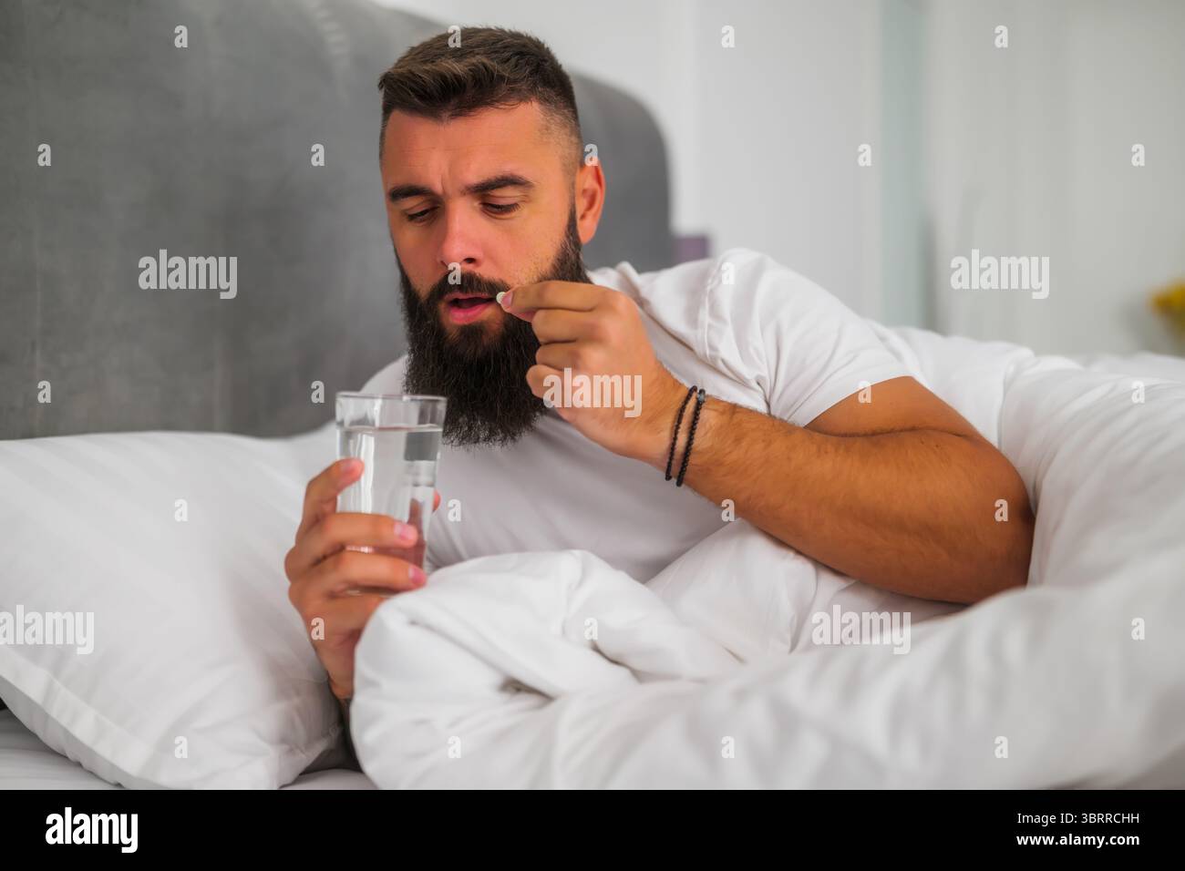 L'uomo non riesce a dormire. Sta prendendo pillole per dormire. Foto Stock