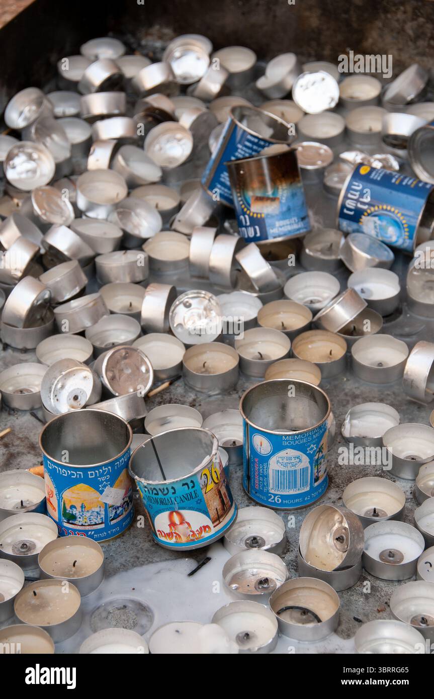 I contenitori di candele blu e di metallo e le candele di tè bruciate come memoriale per i morti dell'Ebraismo vengono gettati fuori da una tomba in Israele. Foto Stock
