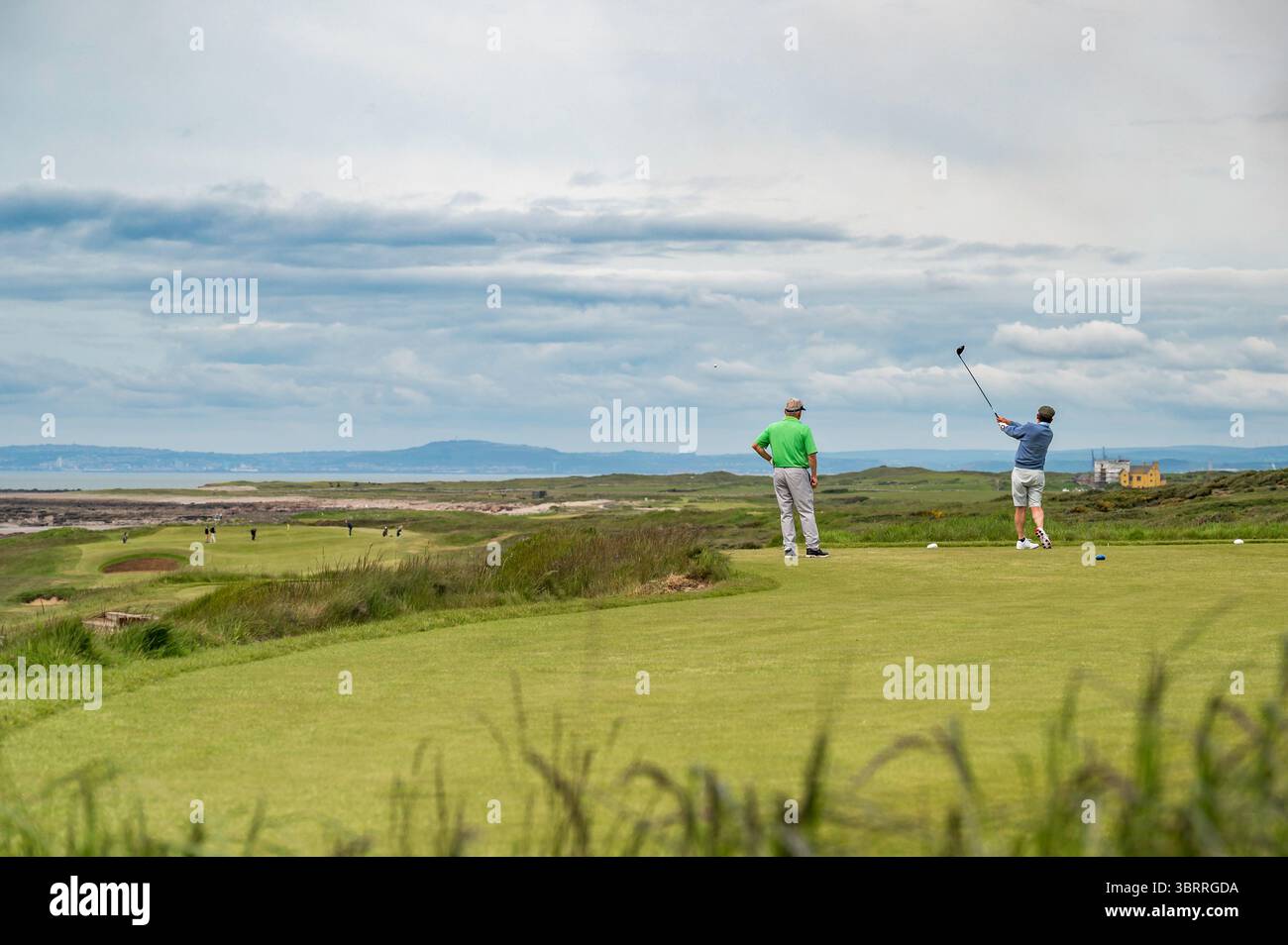 Due golfisti che giocano su un campo in stile links in Galles, Regno Unito, in una giornata primaverile overcast Foto Stock