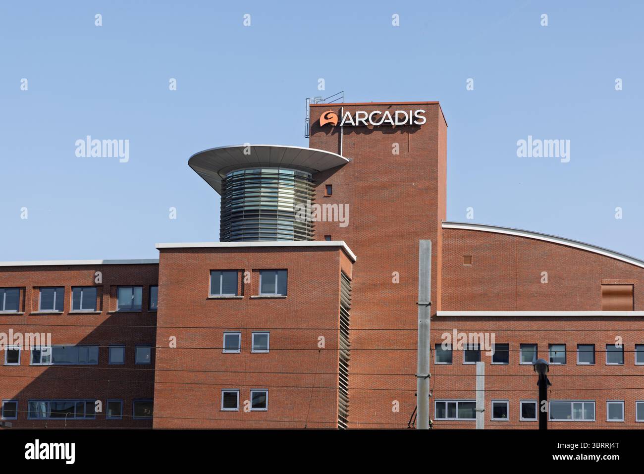 Un grande edificio in mattoni con una distintiva struttura circolare sul tetto, caratterizzato dal logo 'Arcadis' ben visibile. Amersfoort, Paesi Bassi Foto Stock