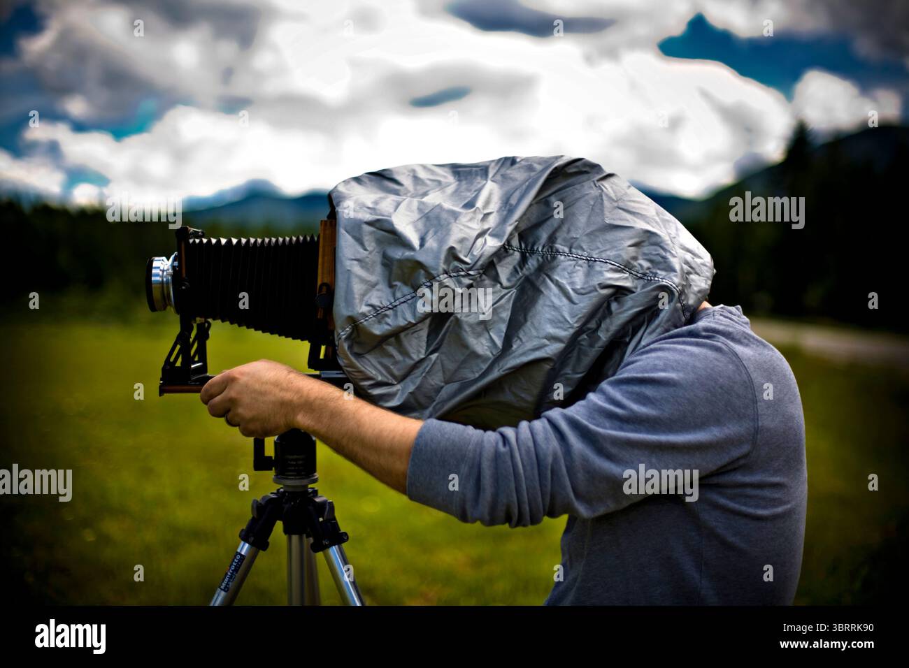 Un uomo scatta una foto con la sua fotocamera di grande formato in un campo vicino al lago Leigh nel Montana. Foto Stock