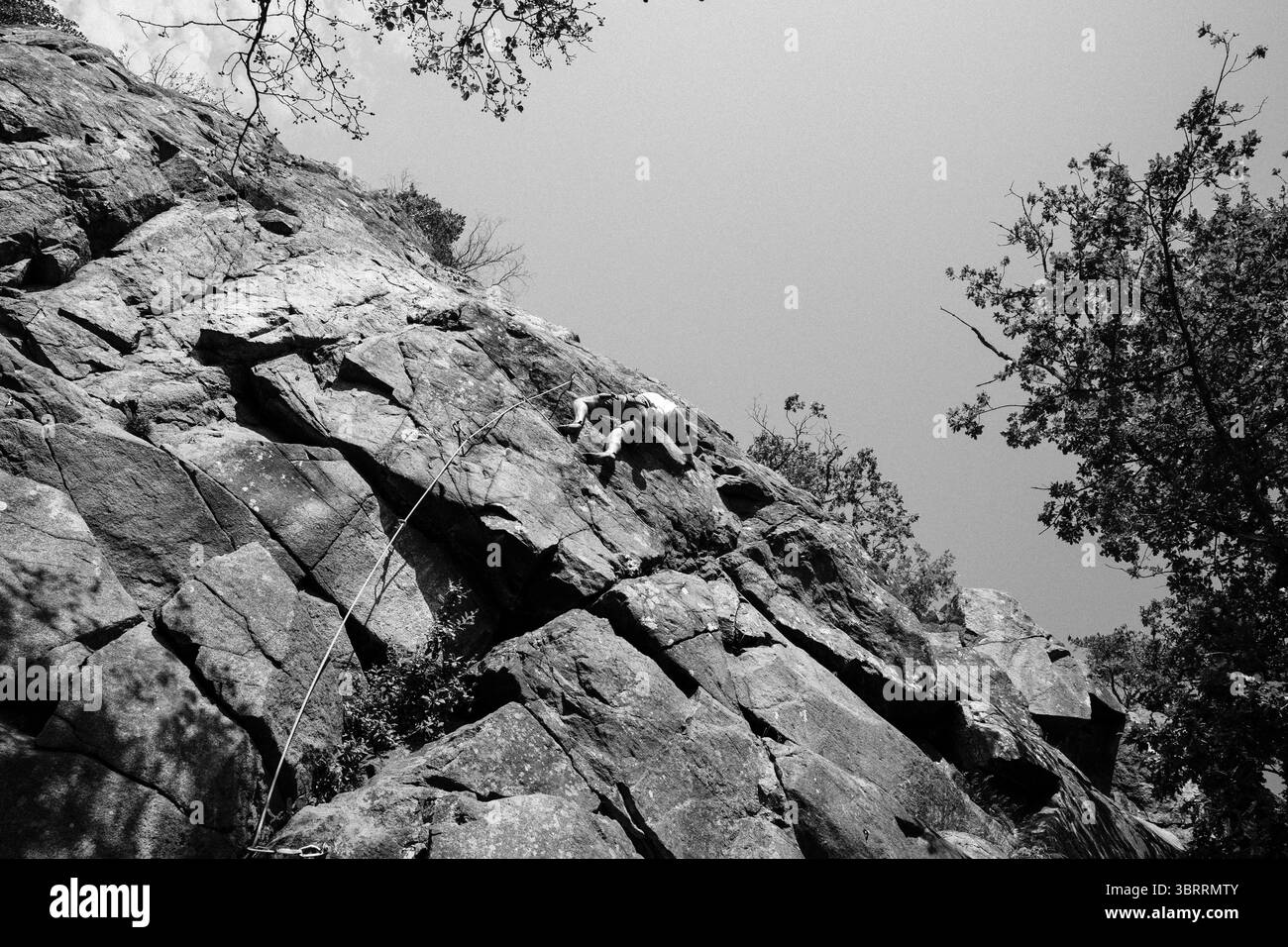 uomo che arrampica su un'enorme roccia mentre si arrampica all'aperto Foto Stock