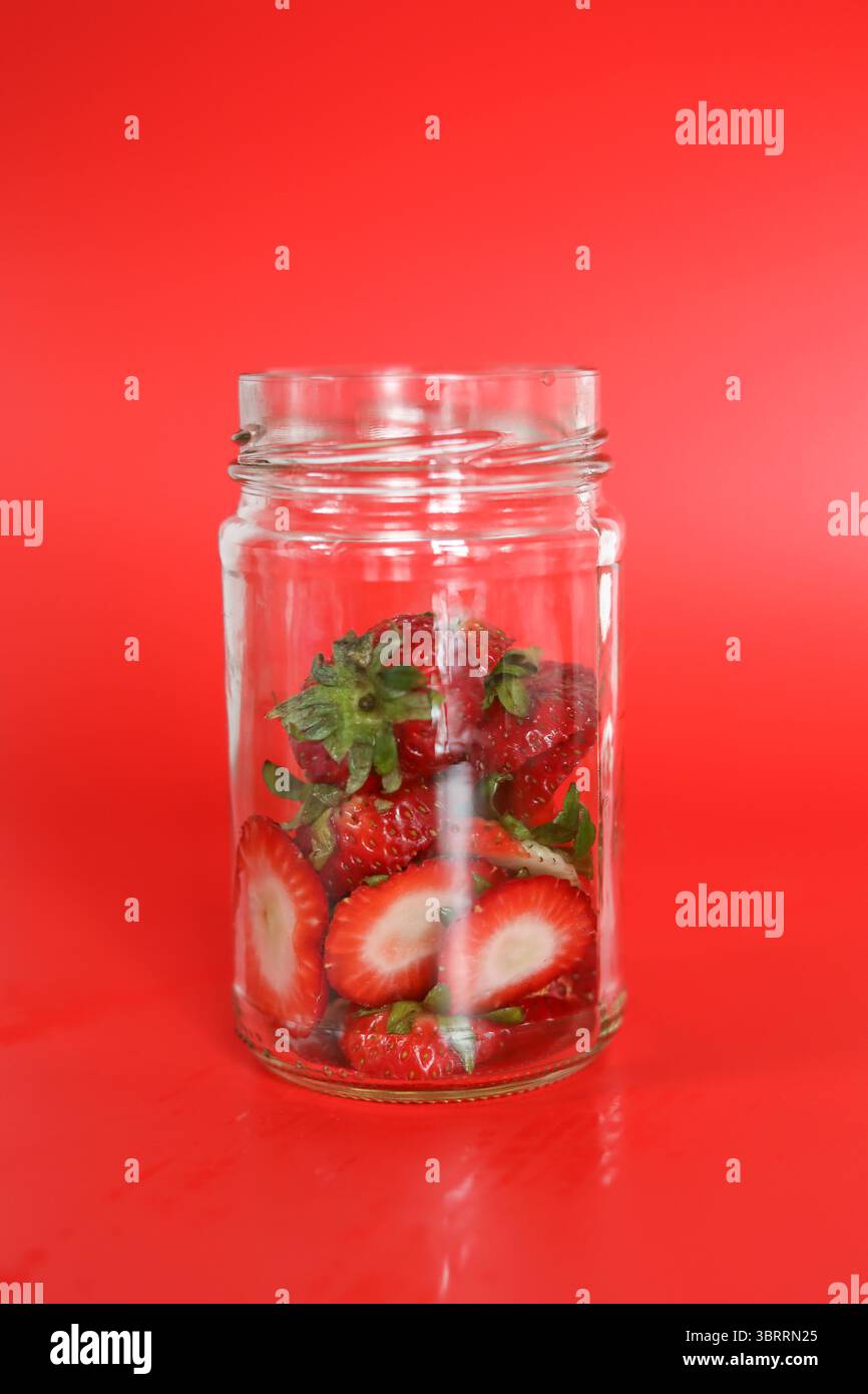 Vasetto in vetro trasparente con cime di fragole per sciroppo di fragole Foto Stock