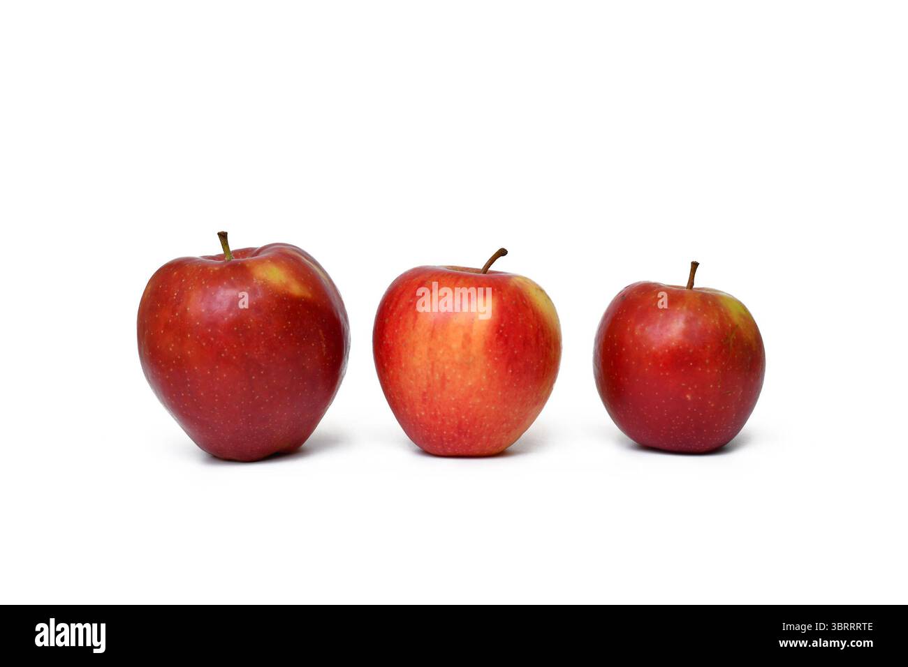 Tre mele rosse di diverse dimensioni. Concetto di confronto, crescita e variazione naturale della frutta Foto Stock