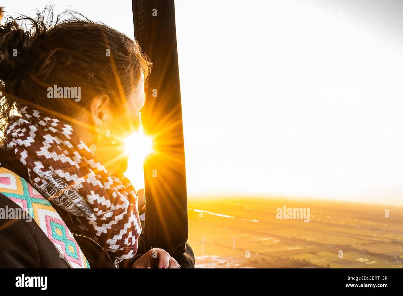 Donna che si gode un giro in mongolfiera con vista sul tramonto dei Paesi Bassi. Passeggero donna in un'avventura panoramica aerea Foto Stock
