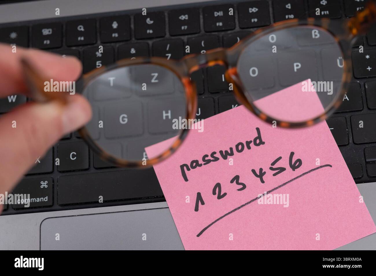Rischio per la sicurezza sulla scrivania: Un foglio di carta con la password non sicura 123456 aperta su un laptop Foto Stock Rischio per la sicurezza sulla scrivania: Un foglio di carta con la password non sicura 123456 aperta su un laptop Foto Stock