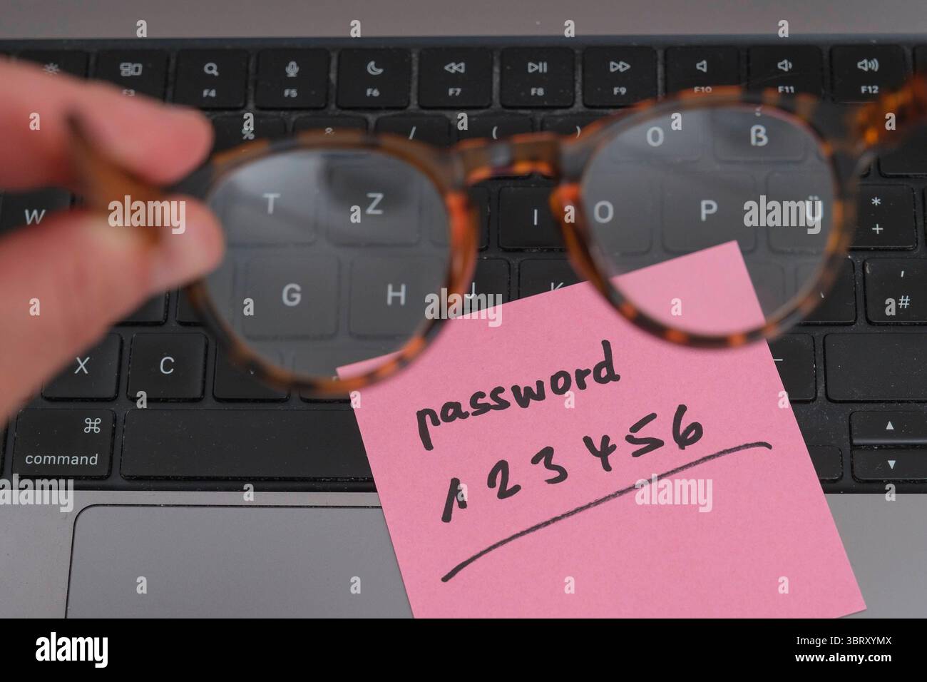 Sicherheitsrisiko auf dem Schreibtisch: Ein Zettel mit dem unsicheren Passwort 123456 liegt offen auf einem laptop, ein klassisches Beispiel für fahrlässigen Umgang mit sensiblen Zugangsdaten. *** Rischio di sicurezza sulla scrivania: Un pezzo di carta con la password non sicura 123456 aperta su un laptop è un classico esempio di gestione negligente dei dati di accesso sensibili. Nordrhein-Westfalen Deutschland, Germania GMS19551 Foto Stock