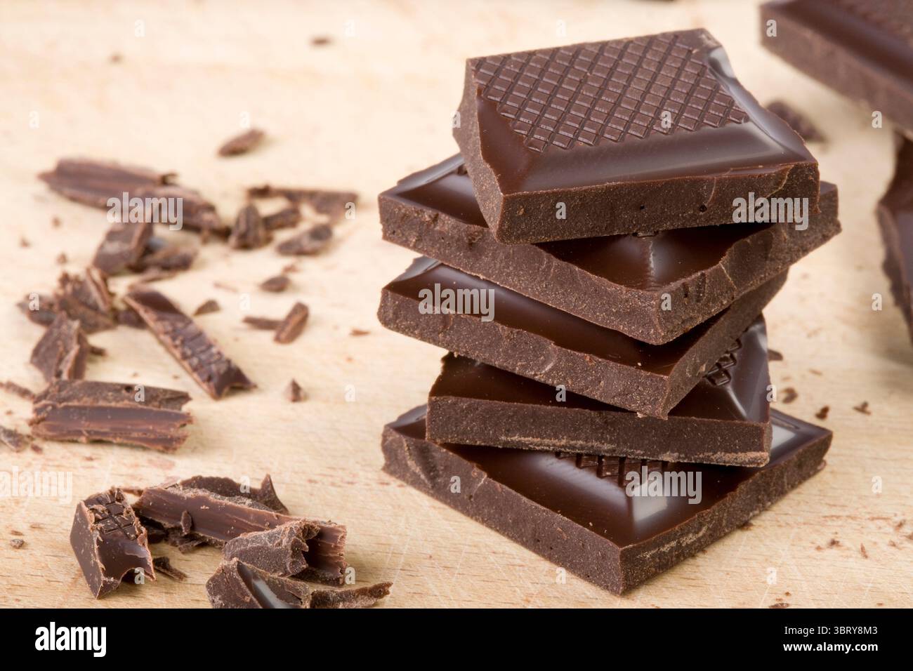 Pezzi di cioccolato impilati su un tagliere di legno Foto Stock