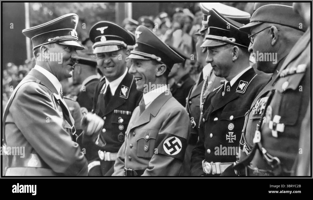 Adolf Hitler in uniforme militare in conversazione con Joseph Goebbels che indossa una fascia da braccio di svastica, durante il Congresso generale del Partito NSDAP a Dessau; accanto a Joseph Goebbels, il leader personale delle SS di Hitler Julius Schaub e il capo della stampa del Reich NSDAP, il dottor otto Dietrich Dessau, Germania nazista Foto Stock