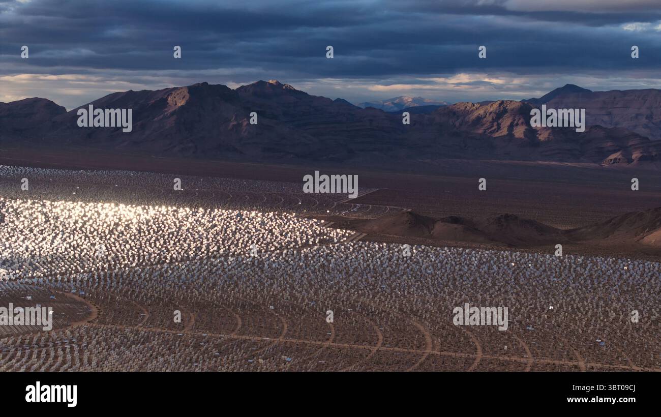 Veduta aerea del sistema di generazione dell'energia solare elettrica di Ivanpah scintillante come un vasto lago riflettente contro il paesaggio desertico, incorniciato da dist Foto Stock