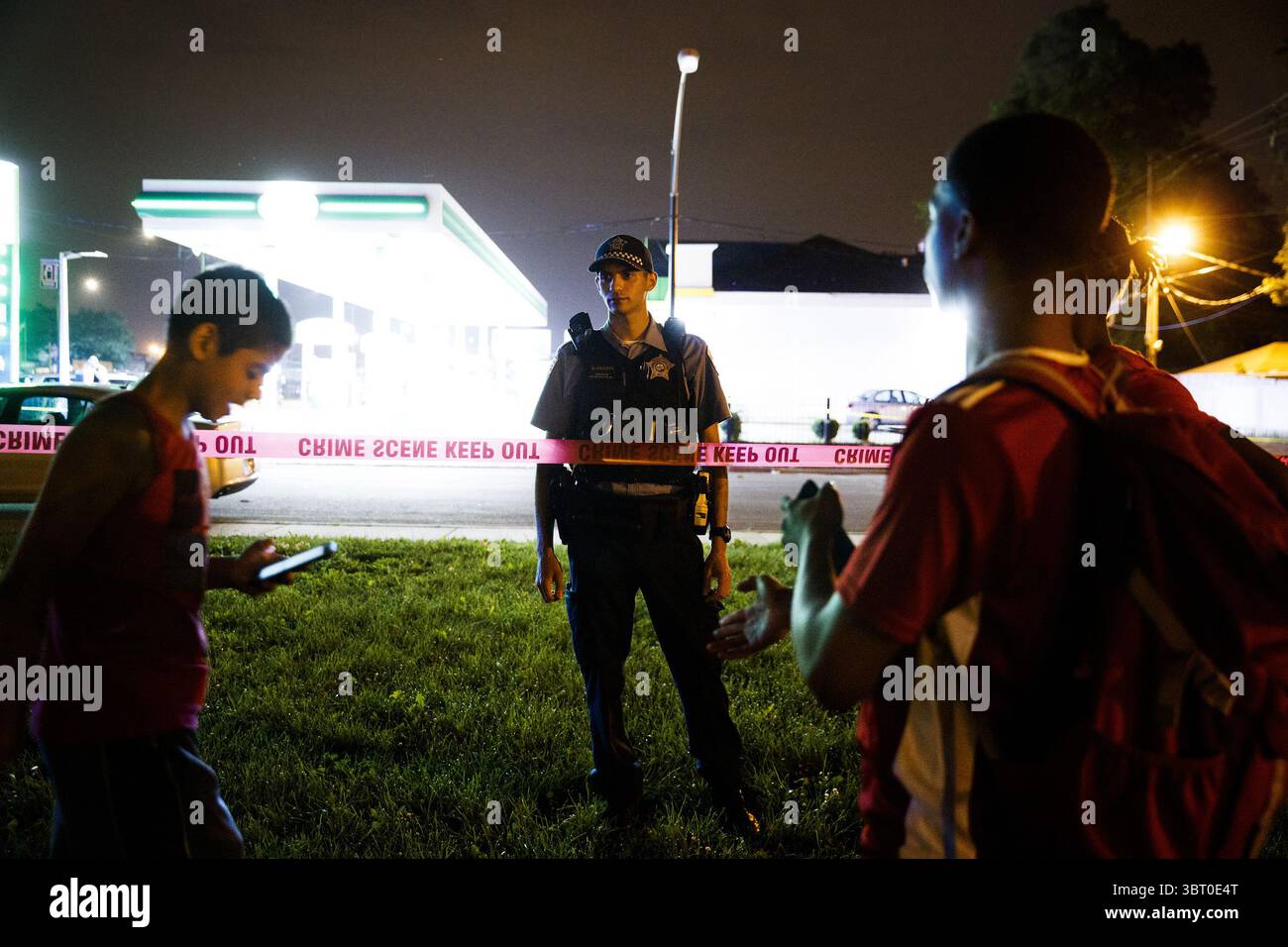24 giugno 2018 - Chicago, il, USA - un ufficiale parla con un gruppo di adolescenti e astanti sulla scena in cui un uomo di 28 anni è stato colpito alle gambe e indietro mentre camminava sul marciapiede nel blocco 2400 di West 56th Street sabato 23 giugno 2018 a Chicago, Ill. (Immagine di credito: © Armando L. Sanchez/TNS via ZUMA Wire) Foto Stock