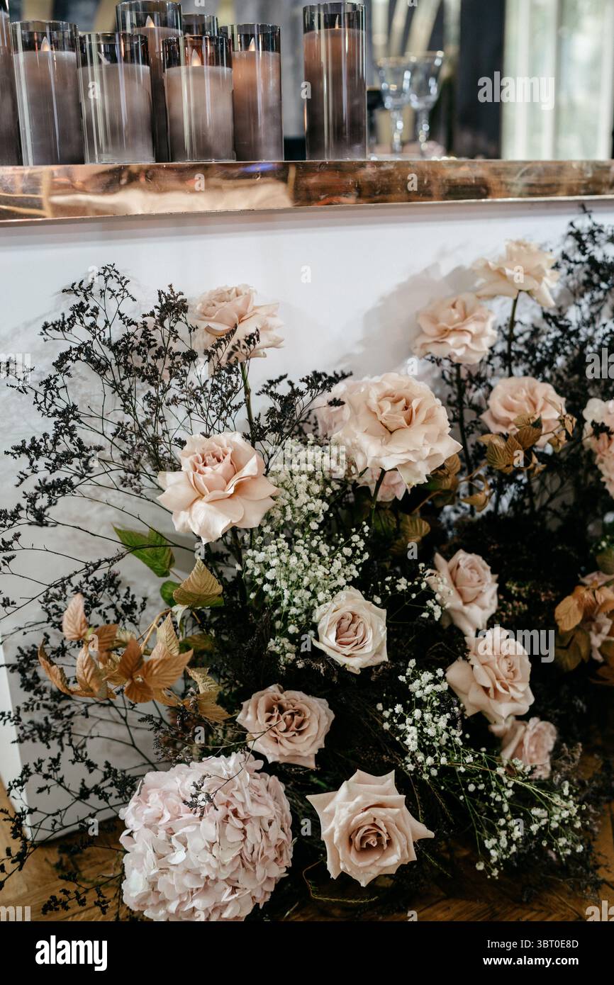 Un elegante allestimento floreale con rose e candele crea un ambiente lussuoso, perfetto per ambienti romantici e arredi sofisticati. Foto Stock