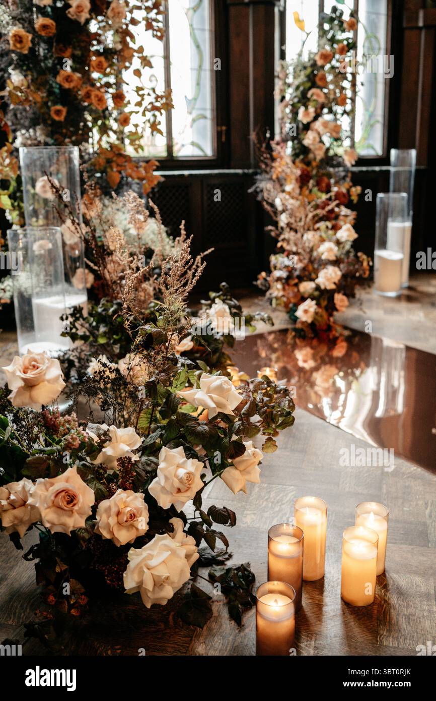 Un sofisticato allestimento floreale caratterizzato da rose e candele in un interno rustico, che crea un ambiente romantico ed elegante con illuminazione soffusa e Foto Stock