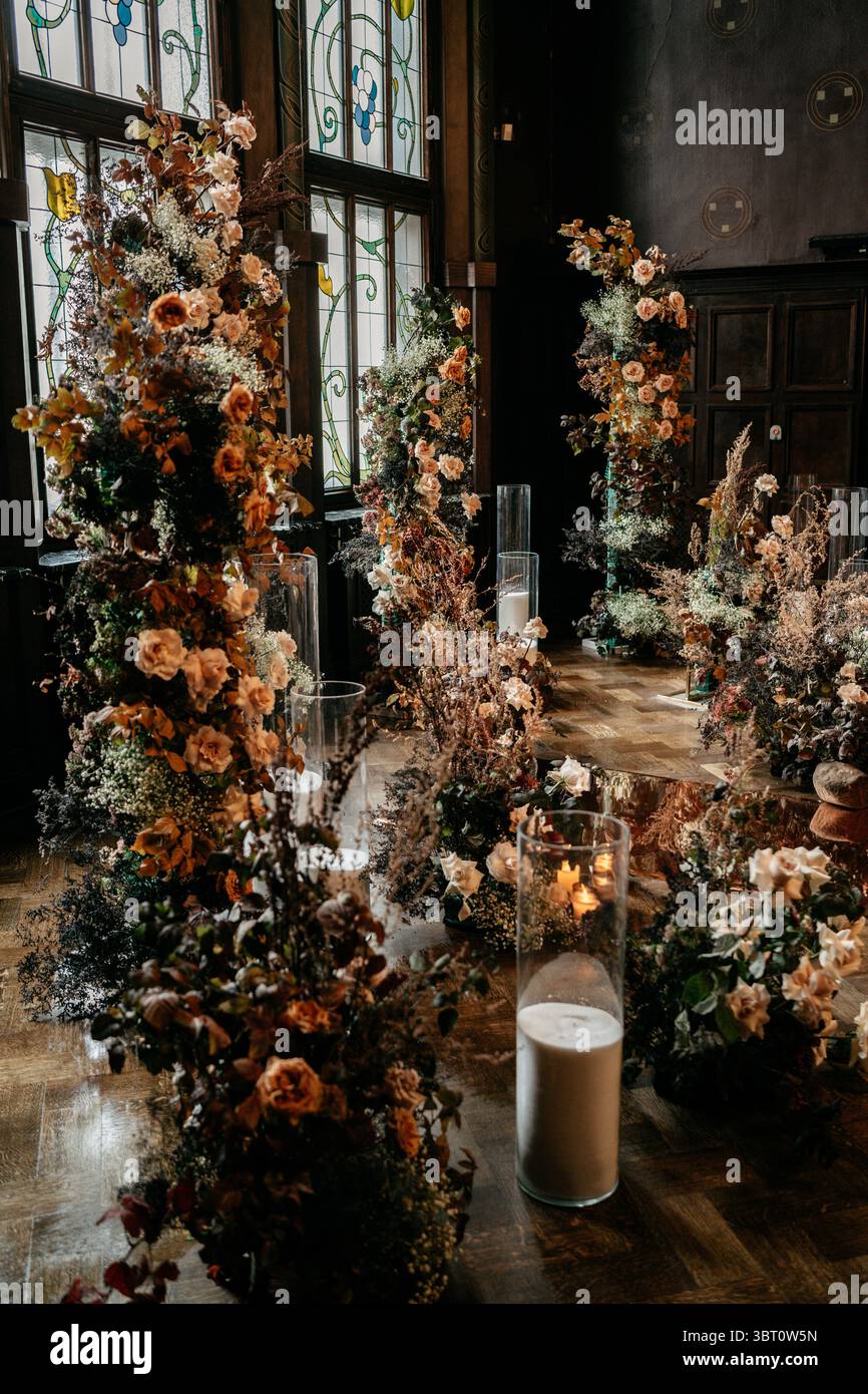 Elegante disposizione floreale interna con luce calda e vetrate colorate, che creano un ambiente senza tempo e romantico impreziosito da elementi naturali e lattine Foto Stock