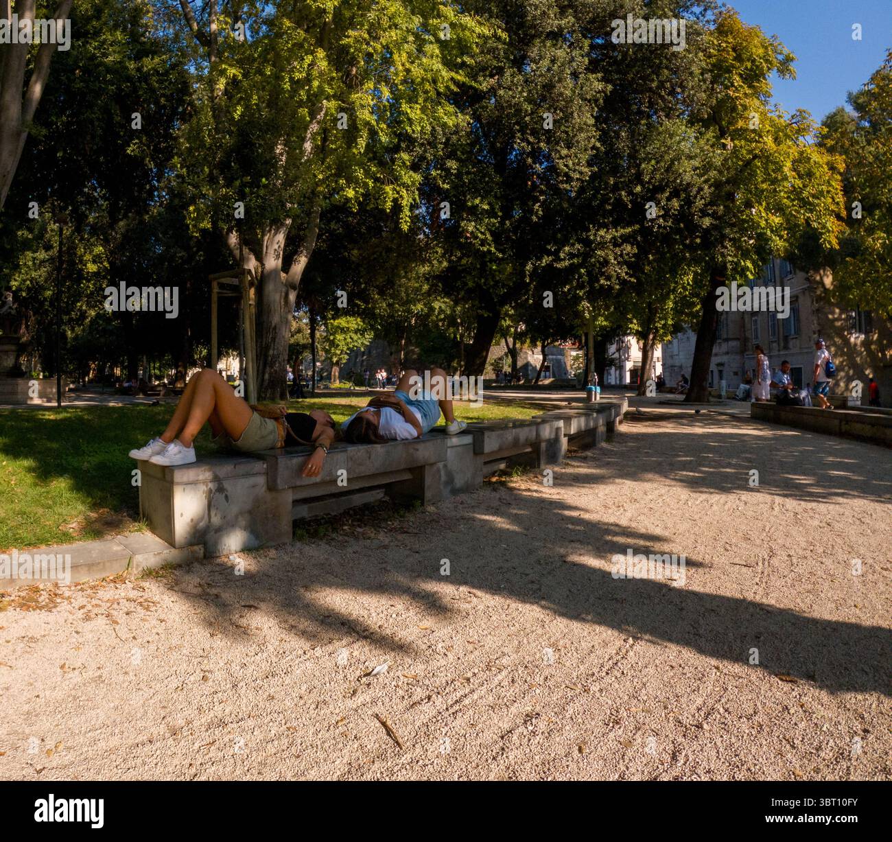 Spalato, Croazia - 8 settembre 2023: Due persone si rilassano su una panchina in un parco, godendosi il sole di fine estate e l'atmosfera tranquilla. Foto Stock