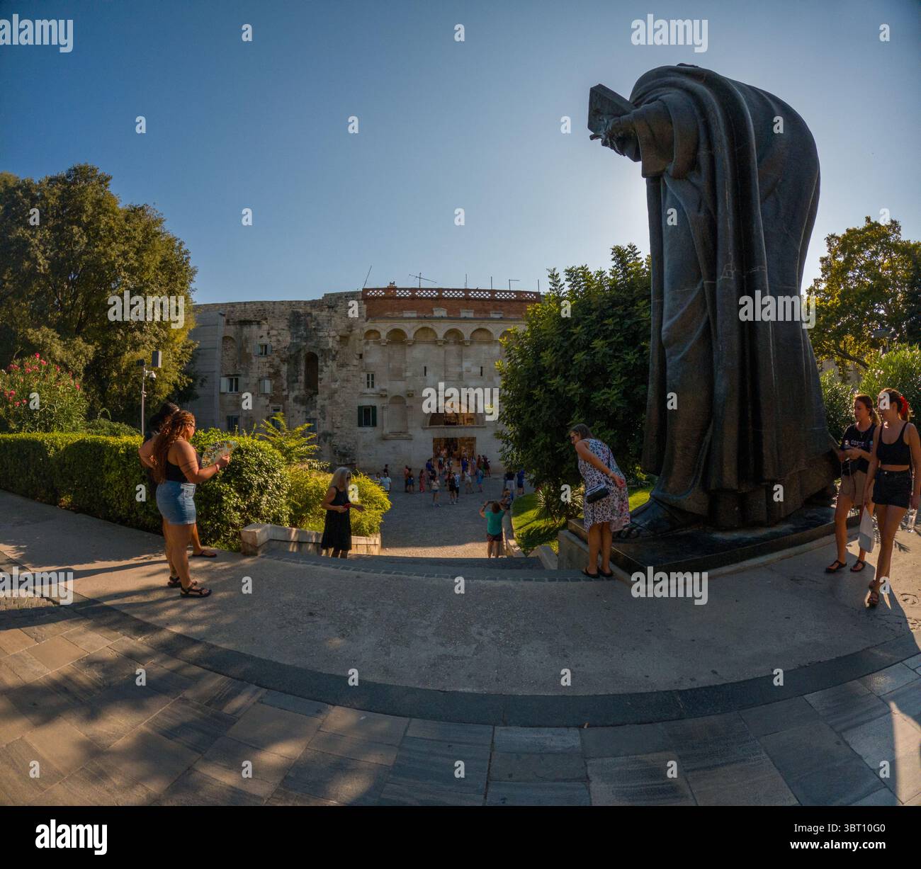 Spalato, Croazia - 8 settembre 2023: I turisti visitano la statua di Gregorio di Nin e il Palazzo di Diocleziano. Stanno esplorando i siti storici e tak Foto Stock