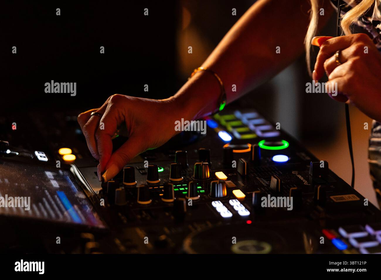 Primo piano di un DJ e delle sue mani che si mescolano sui suoi mazzi, DJ a bassa profondità di campo, mixando musica, toccando le manopole, quadranti e interruttori Foto Stock