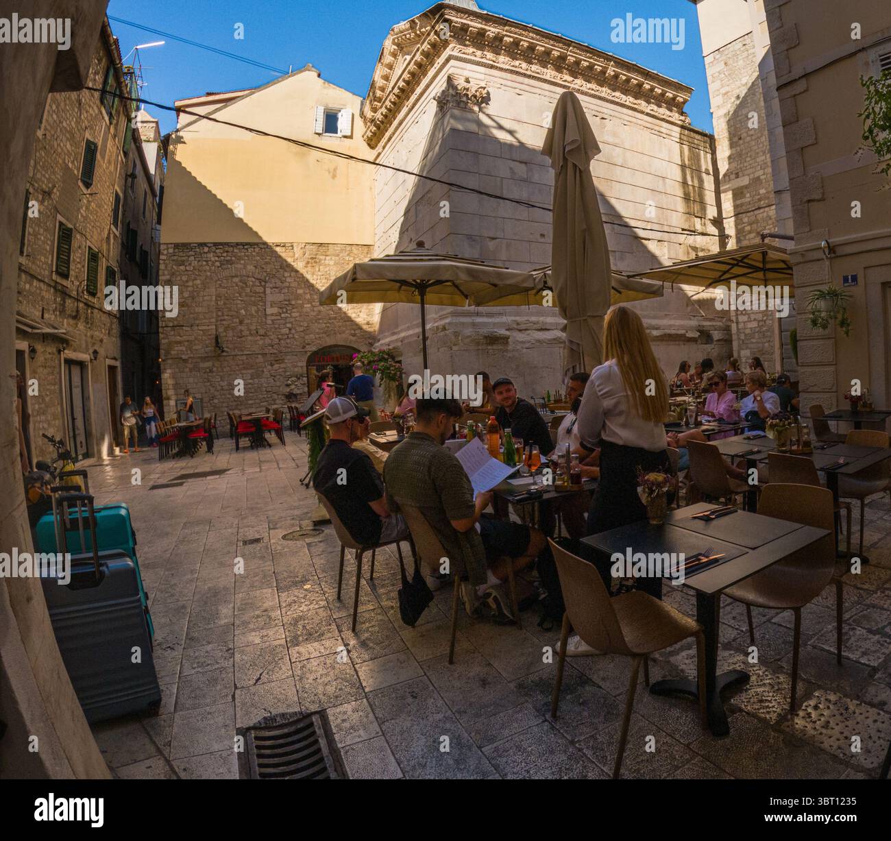Spalato, Croazia - 8 settembre 2023: I turisti cenano in un caffè all'aperto, gustando la cucina locale e l'atmosfera nel centro storico della città. Foto Stock