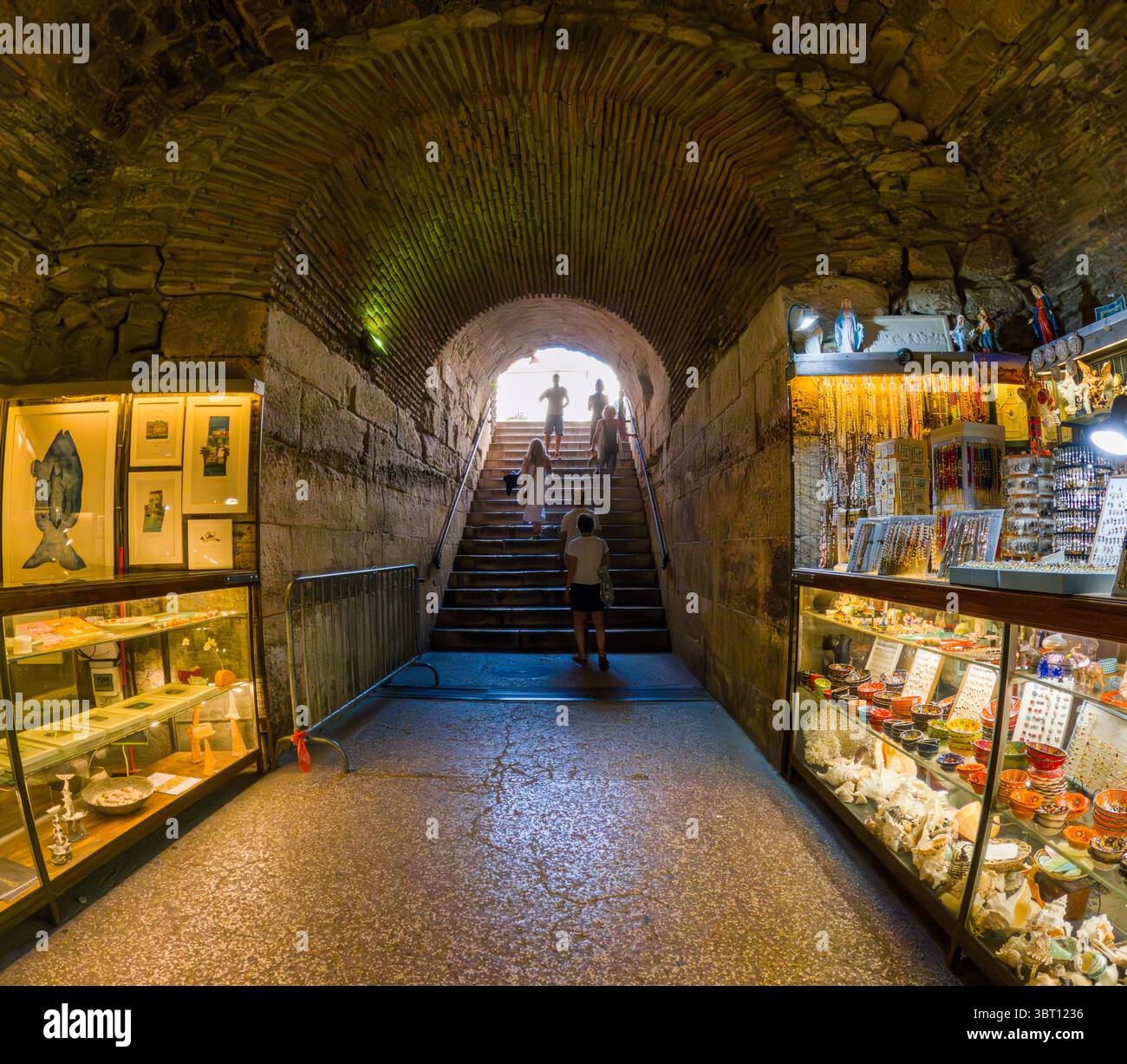 Spalato, Croazia - 8 settembre 2023: I turisti salgono le scale nelle cantine del Palazzo di Diocleziano, curiosando tra i negozi di souvenir che costeggiano l'antico passaggio. Foto Stock
