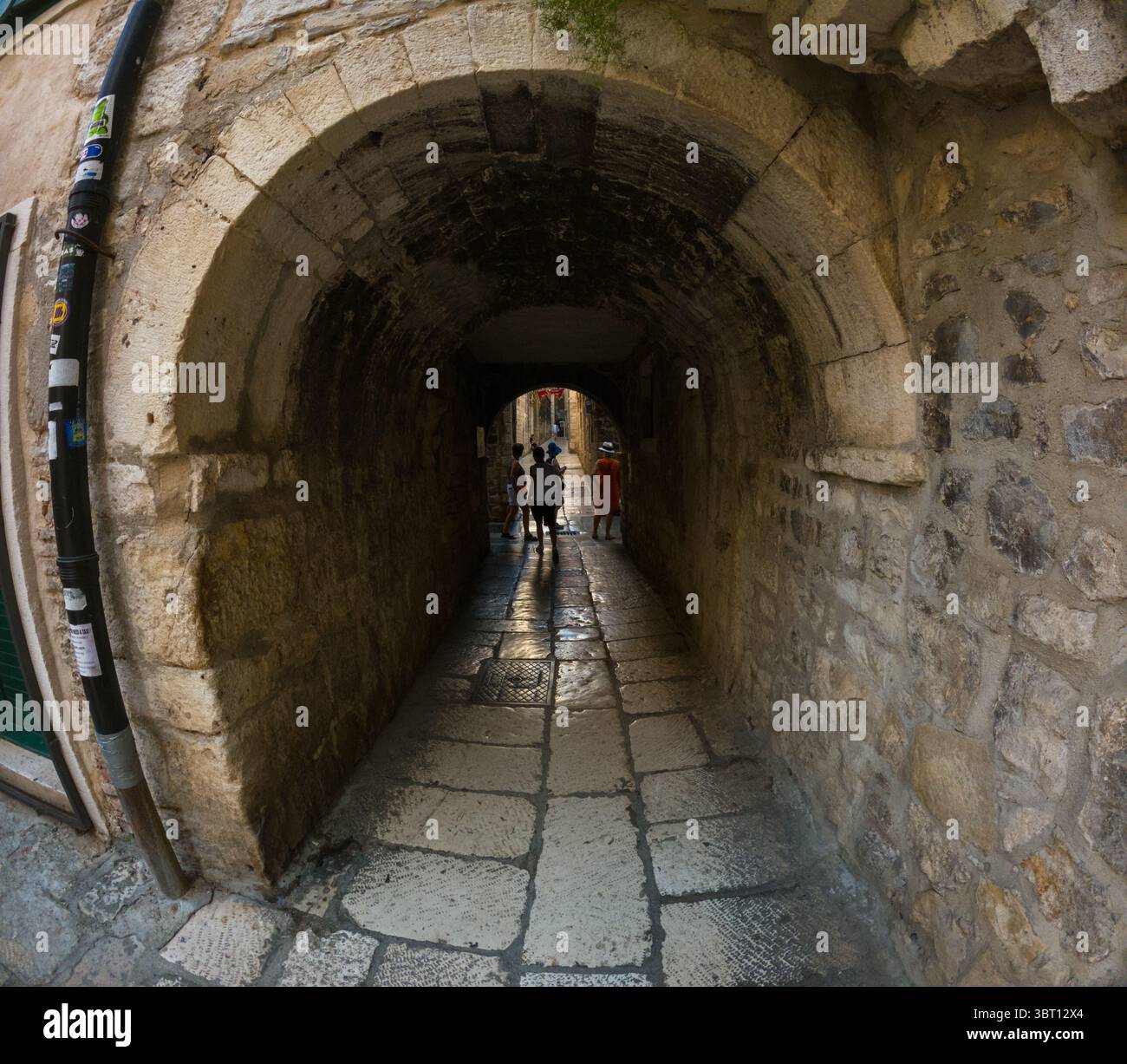 Spalato, Croazia - 8 settembre 2023: I turisti esplorano un tunnel di pietra a Spalato, Croazia. Il tunnel fornisce un passaggio ombreggiato attraverso l'antica città. Foto Stock