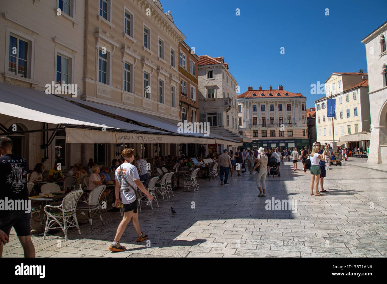 Spalato, Croazia - 8 settembre 2023: I turisti passeggiano per la piazza della città, godendosi i panorami e i suoni del ristorante Kavana Central. Foto Stock