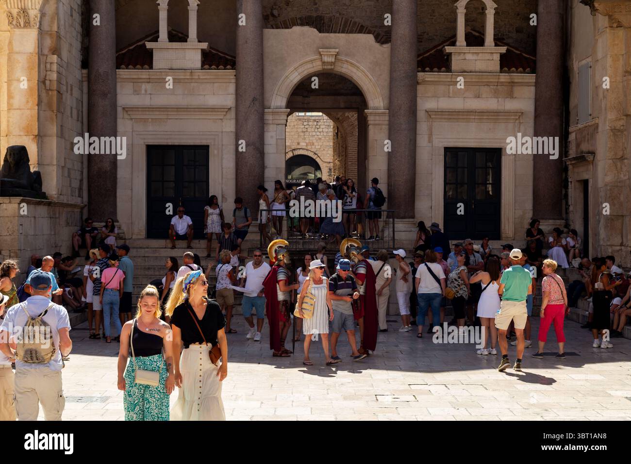 Spalato, Croazia - 8 settembre 2023: I turisti si riuniscono di fronte al Palazzo di Diocleziano, alcuni scattano foto con un uomo vestito da soldato romano. Foto Stock