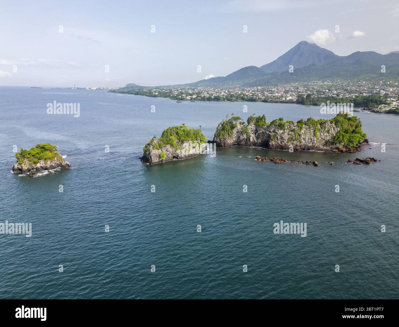 Veduta aerea di isolotti verdeggianti sparsi nel mare ceruleo, in contrasto con la lontana sagoma di una maestosa montagna, Limbe, Sud-Ovest, Camerun. Foto Stock