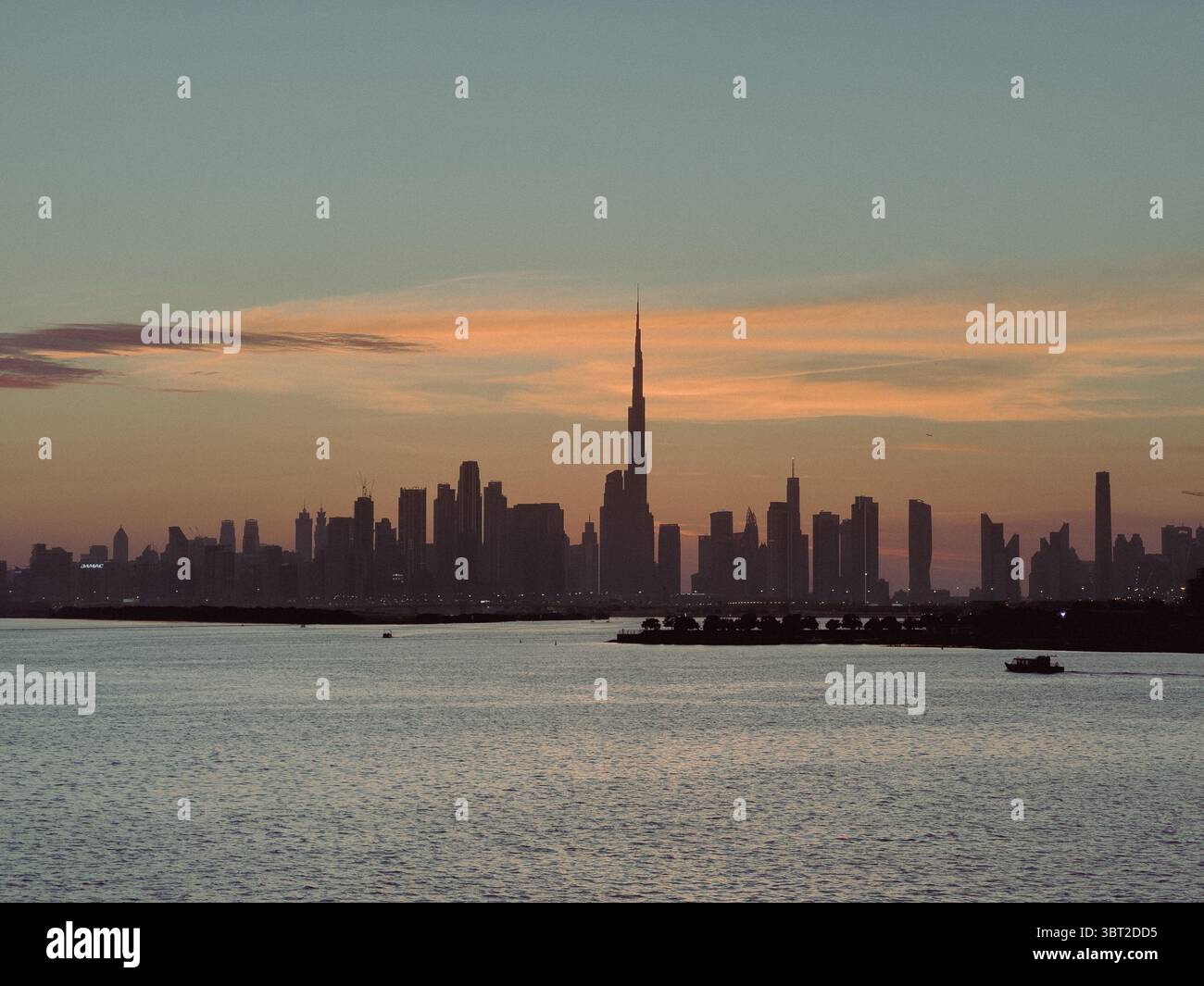 Skyline cinematografico di Dubai al tramonto, silhouette dell'ora d'oro dello skyline, sviluppo del lungomare Foto Stock