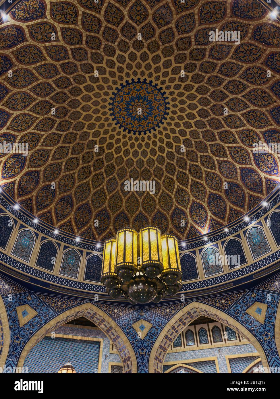 Interni islamici di lusso con dettagli blu e oro, cupola decorata e archi simmetrici Foto Stock