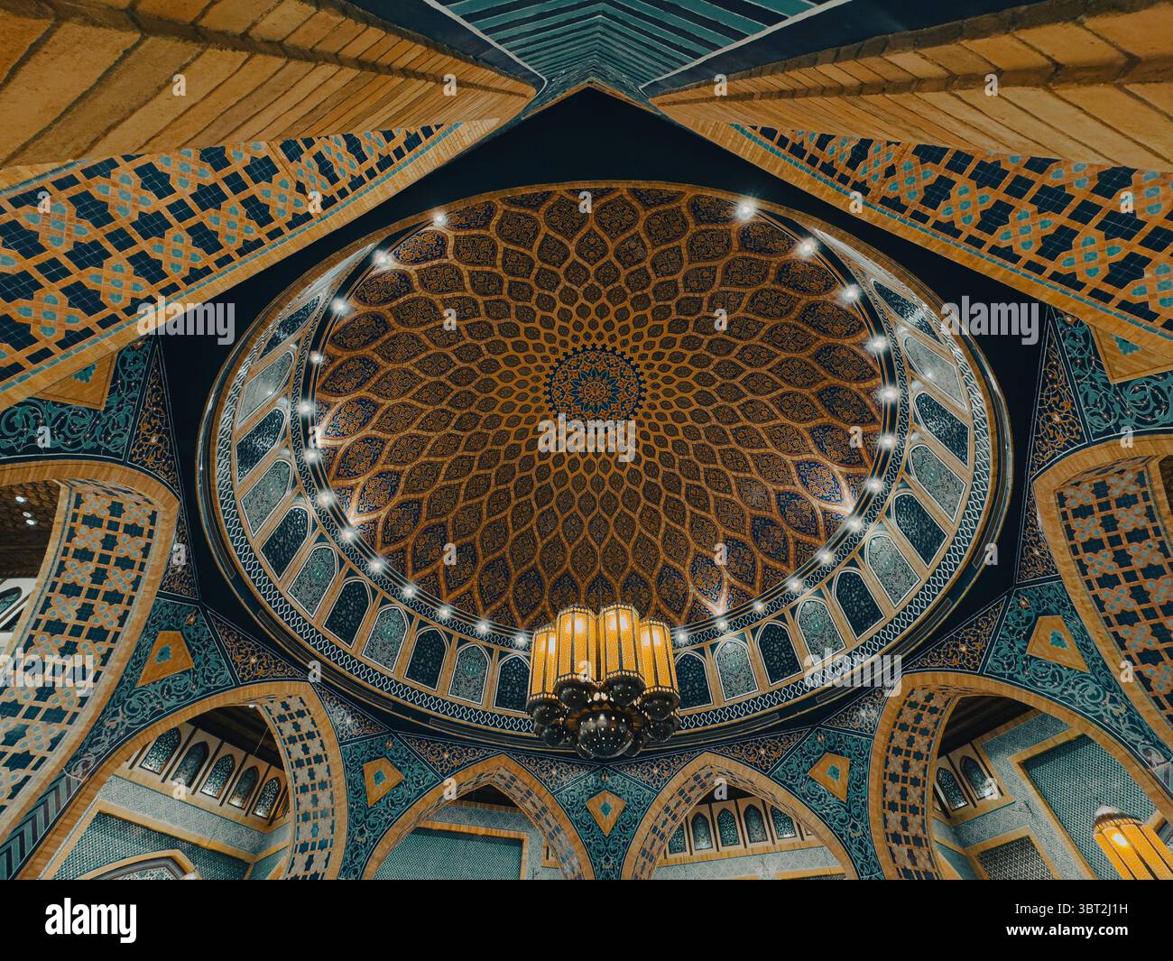 Eleganti motivi blu e oro all'interno della moschea islamica con cupola e archi Foto Stock