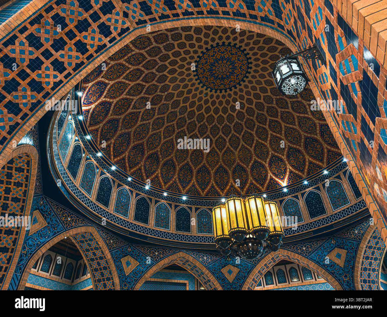 Eleganti motivi blu e oro all'interno della moschea islamica con cupola e archi Foto Stock