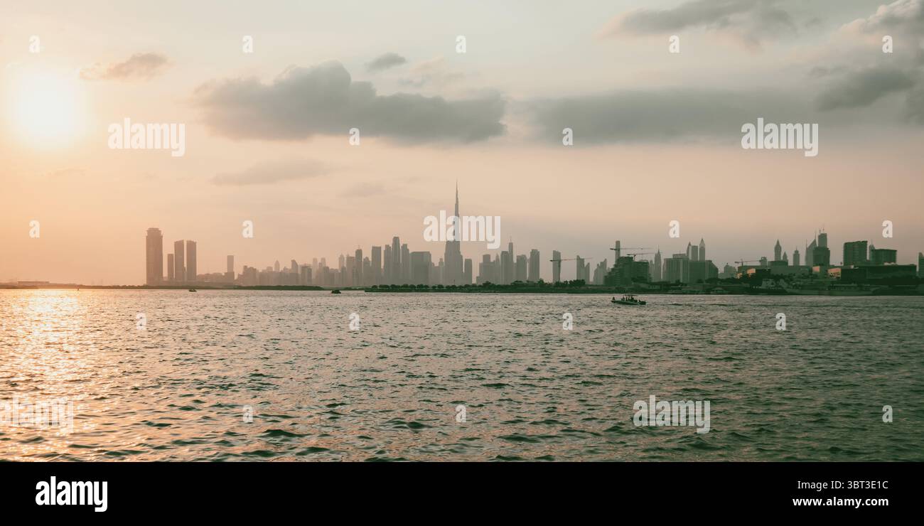 Tramonto sullo skyline della città di Dubai con una vista sul fiume e sulla megacittà dal lungomare Foto Stock
