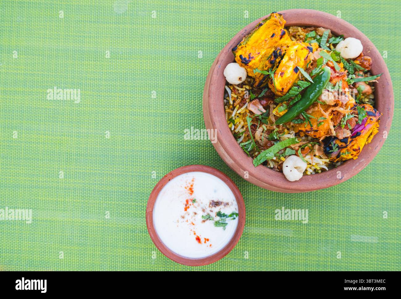 Paneer Biryani di verdure in una ciotola di terra servita con raita e condimenti di yogurt, ristorante indiano a Dubai, ricetta vegetariana per cena a base di piante Foto Stock