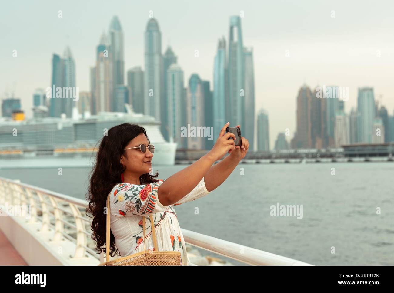 Giovane donna che esplora le viste dello skyline di Dubai. Sta facendo clic sulle foto sull'isola di Palm Jumeirah Foto Stock